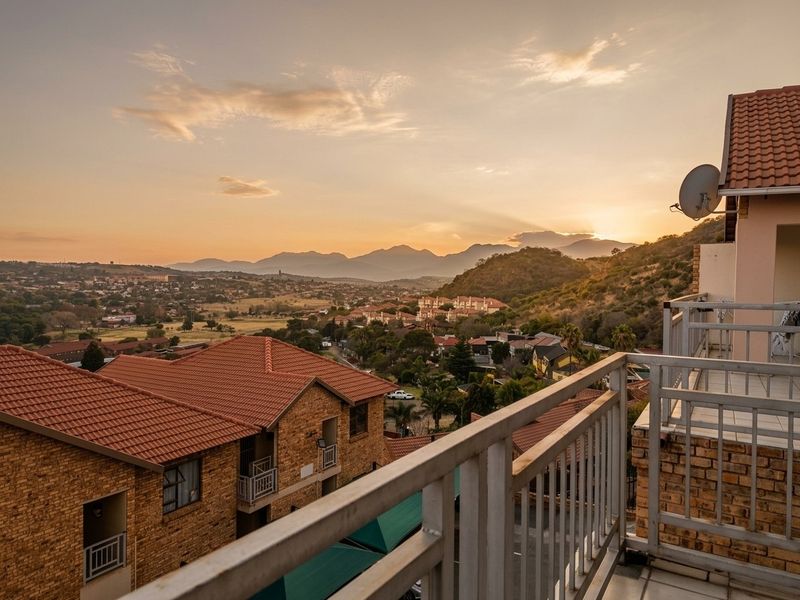 A scenic elevated view overlooking the surrounding residential estate and distant mountains at sunset, captured from a private balcony.