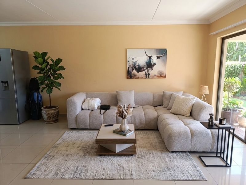 A bright and comfortable living room featuring tiled flooring and a large sliding glass door that provides access to the outdoor area.