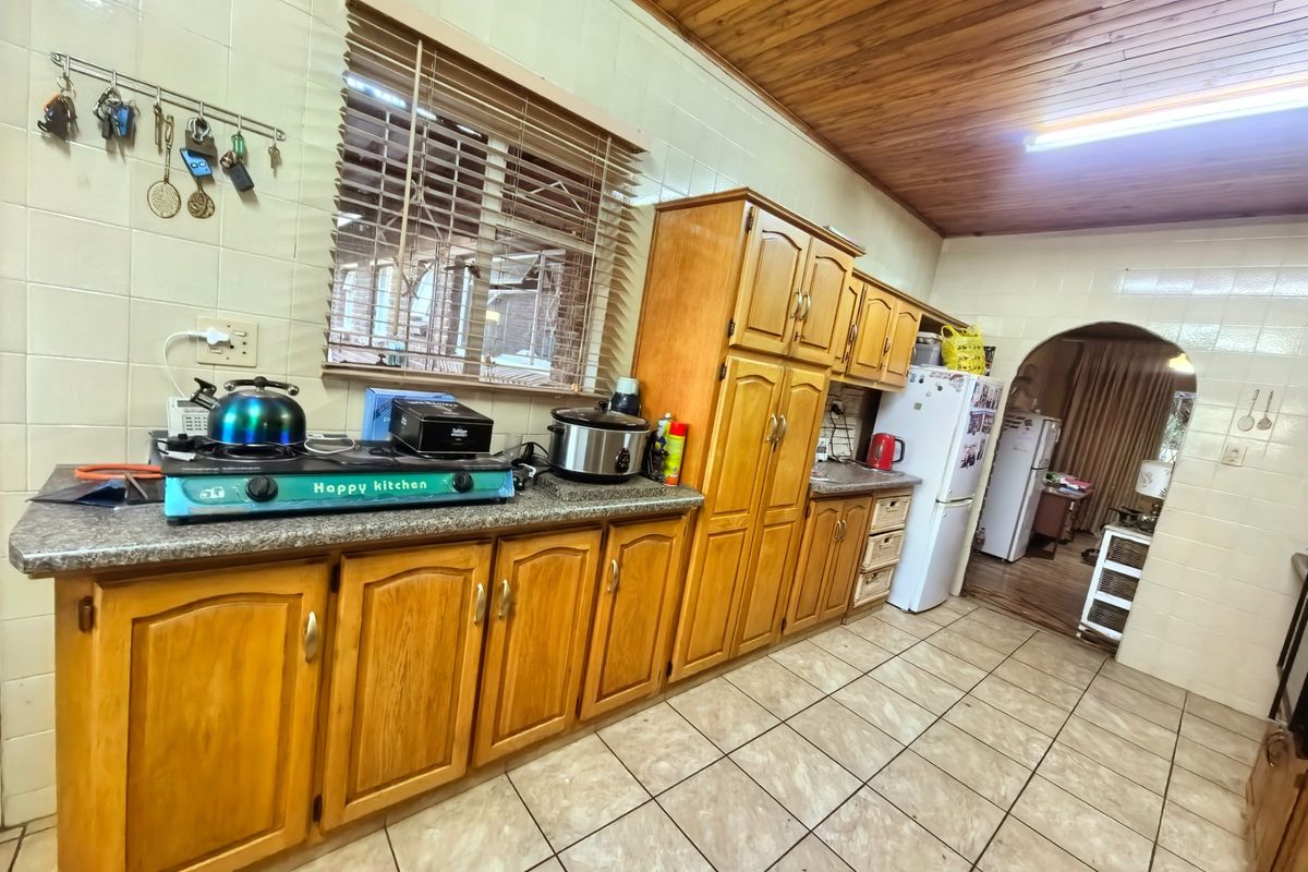 A functional kitchen featuring traditional wooden cabinetry, tiled walls, and a warm timber-paneled ceiling, offering a classic aesthetic with potential for modern updates.