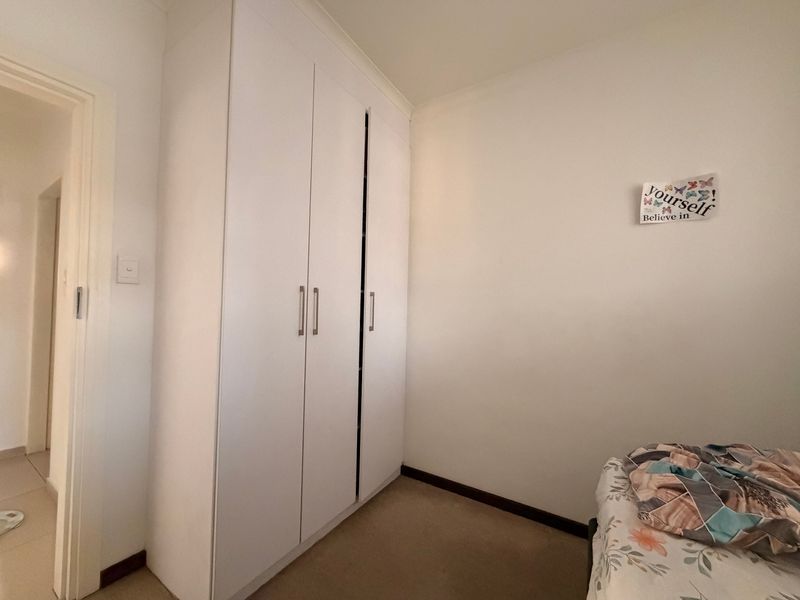 A bedroom featuring a white built-in wardrobe with modern handles and neutral carpeting.