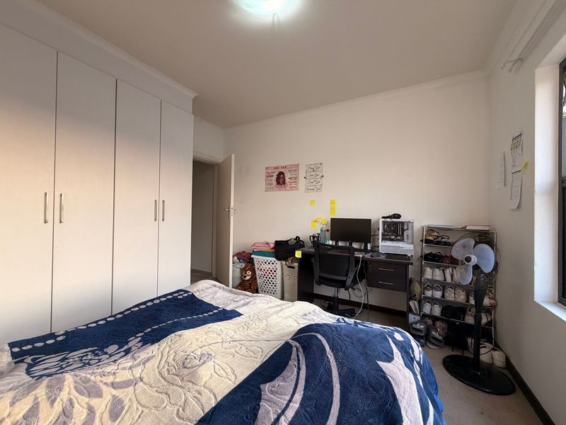 A bedroom featuring built-in cupboards and a window, providing a functional living space.