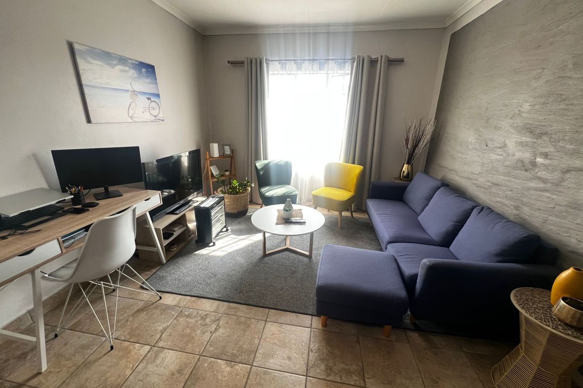 A comfortable living room featuring tiled flooring and a textured feature wall, providing a functional and inviting space for relaxation.