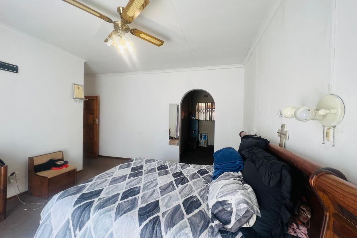 A spacious bedroom featuring a ceiling fan, carpeted flooring, and an arched doorway leading to an adjacent area.