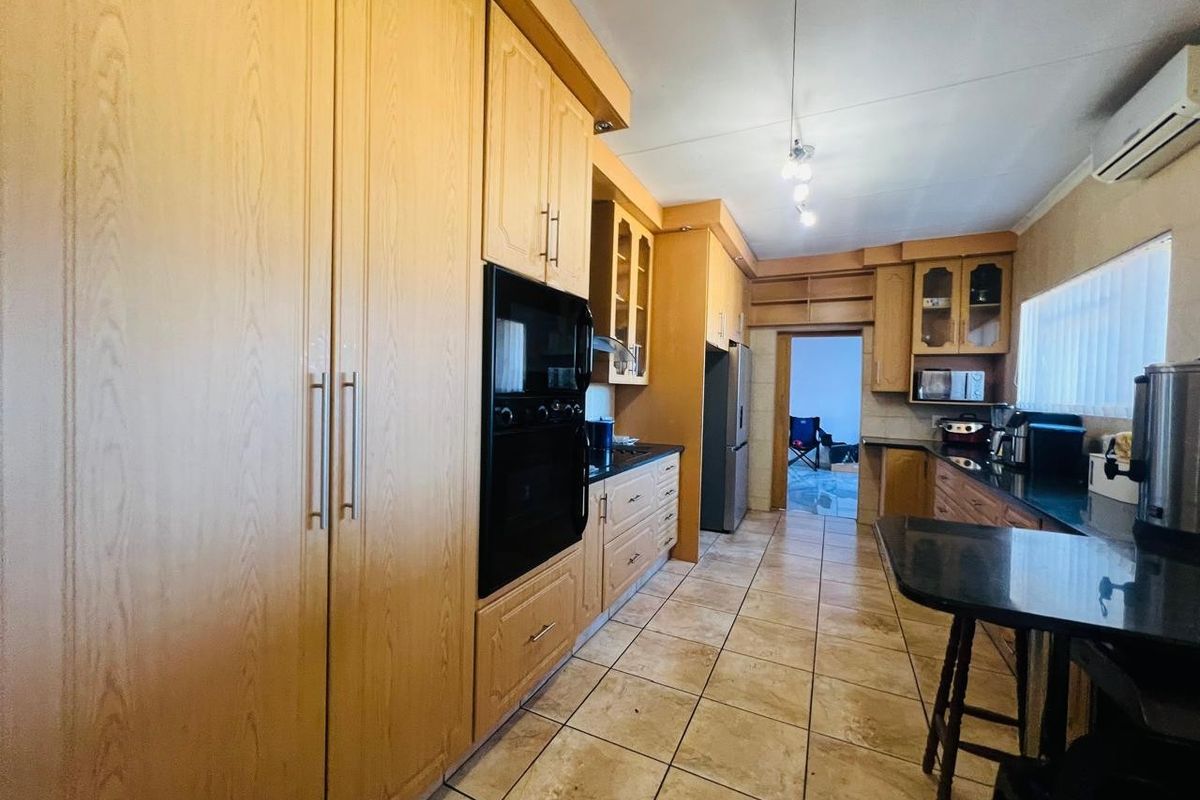 A functional kitchen featuring extensive wooden cabinetry, black granite countertops, built-in oven, and tiled flooring, offering a practical layout for daily use.