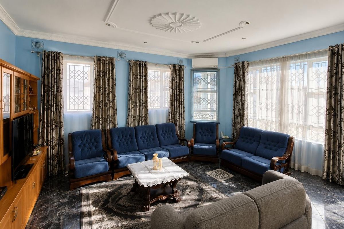 Spacious living room featuring decorative ceiling rose, cornice detailing, tiled flooring, and split-system air conditioning with ample natural light from multiple windows.