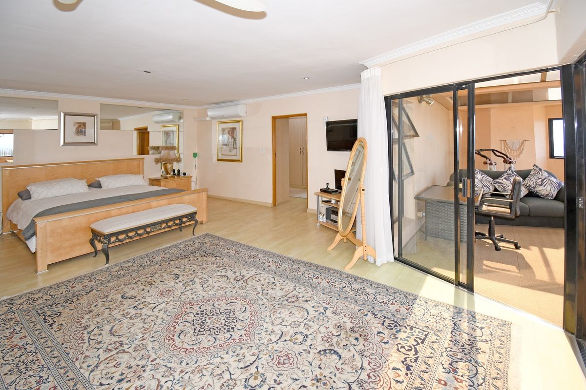 Spacious bedroom featuring laminate flooring, mirrored wall accents, and sliding glass doors leading to an adjoining sunroom or patio area.