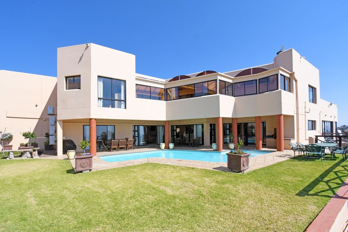 Rear exterior view of a multi-level house featuring a swimming pool, paved patio area, and well-maintained lawn.
