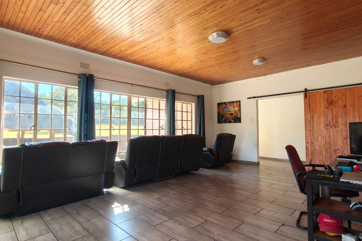 Spacious living area featuring a warm timber tongue and groove ceiling, large windows providing natural light, and a rustic sliding barn door.
