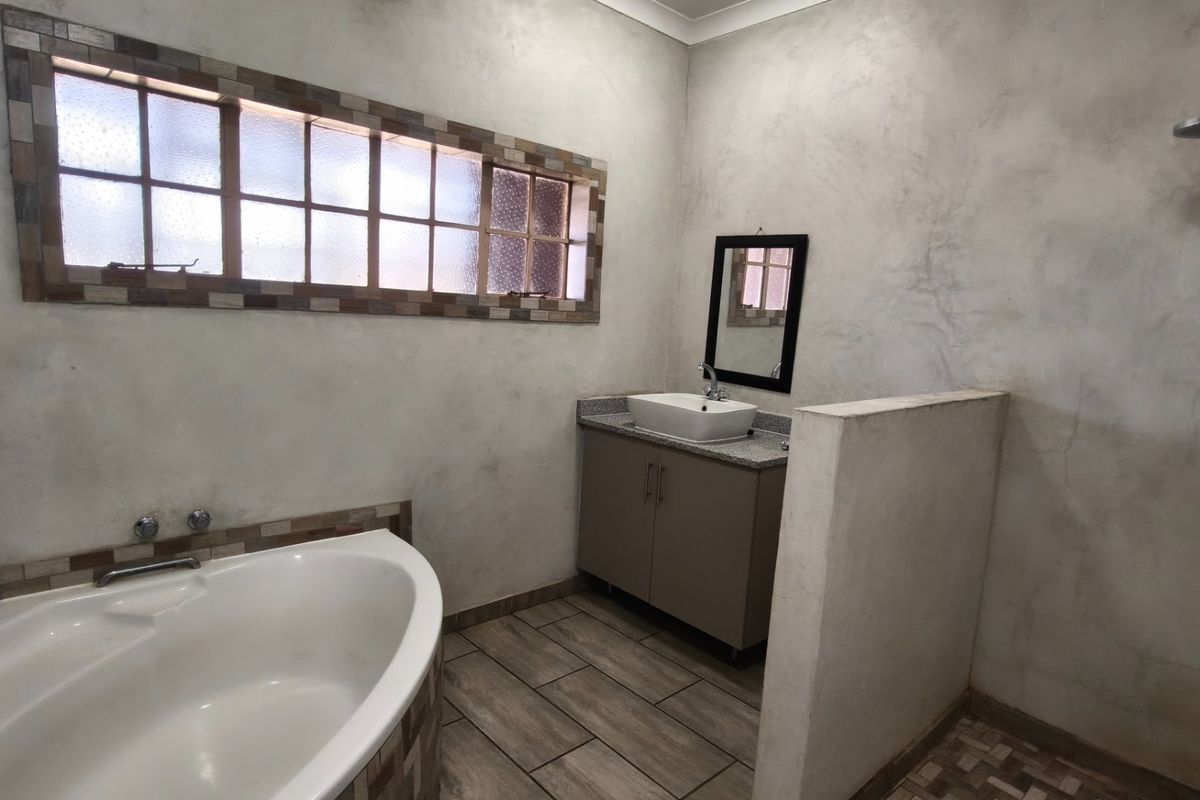 A well-appointed bathroom featuring a corner bathtub, a separate shower area with a half-wall partition, and a modern vanity with a vessel sink.