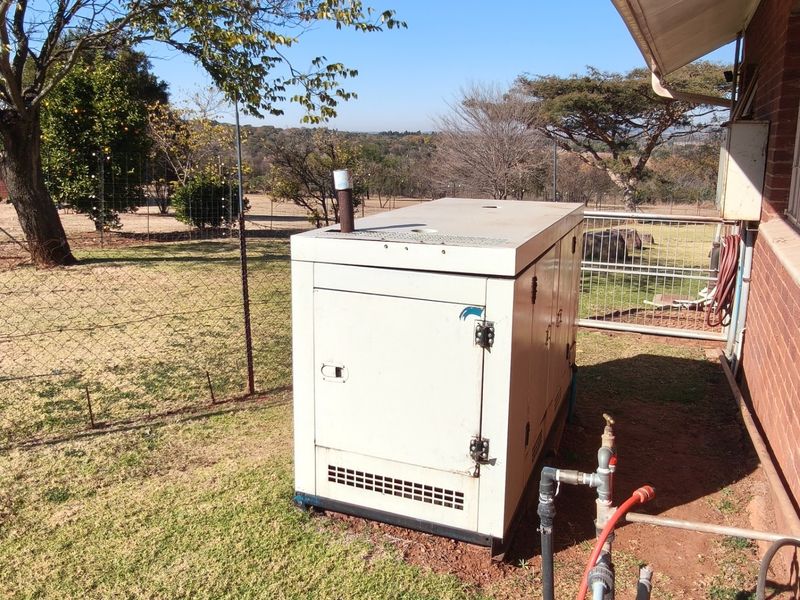 Exterior view of a standby generator unit positioned next to the brick building wall, featuring adjacent external plumbing infrastructure.