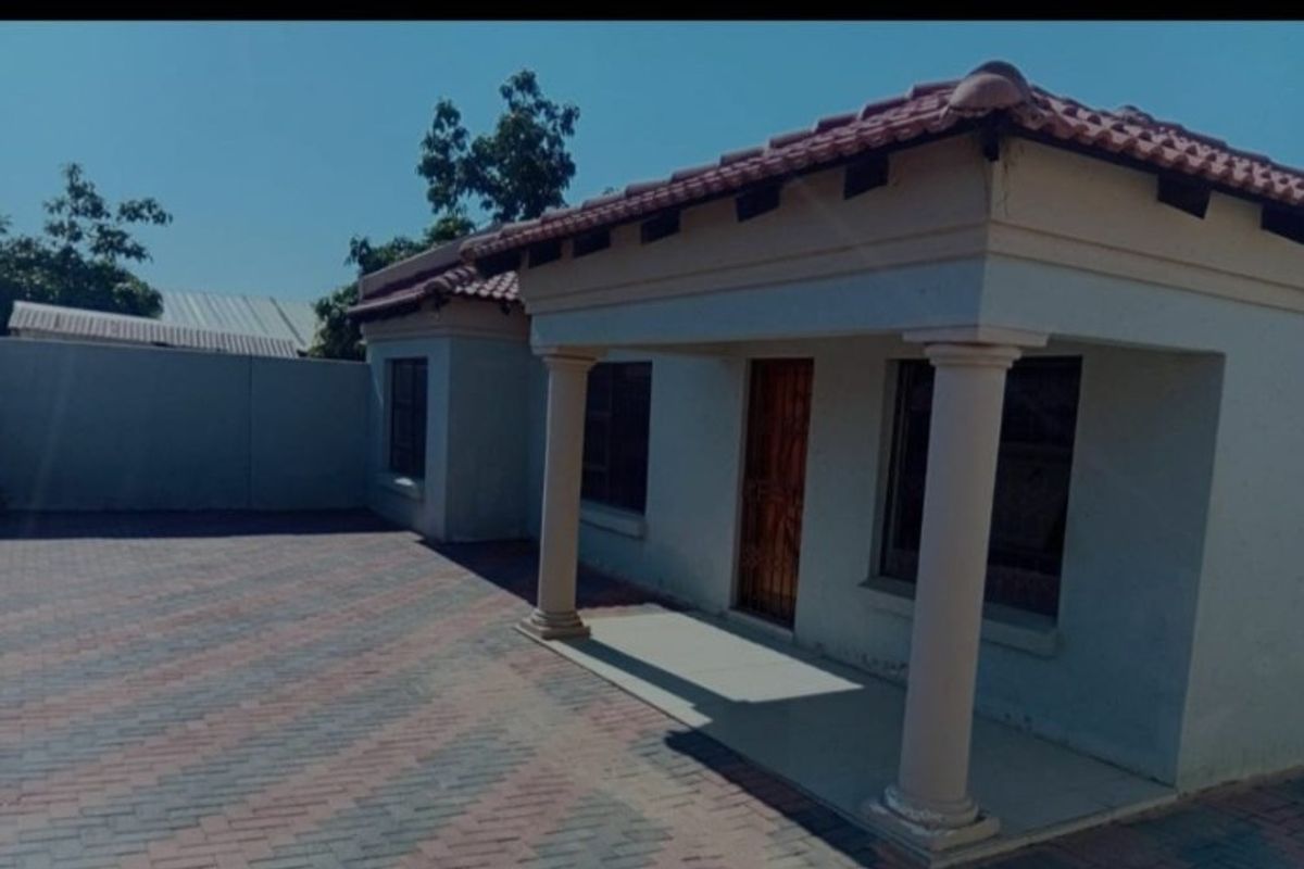 Front view of the property featuring a paved driveway, covered porch with columns, and a tiled roof.