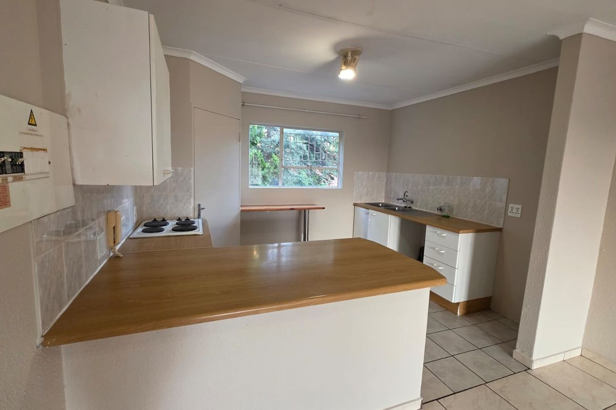 A functional kitchen featuring built-in cabinetry, an electric hob, laminate countertops, and tiled flooring, offering a clean and practical layout.