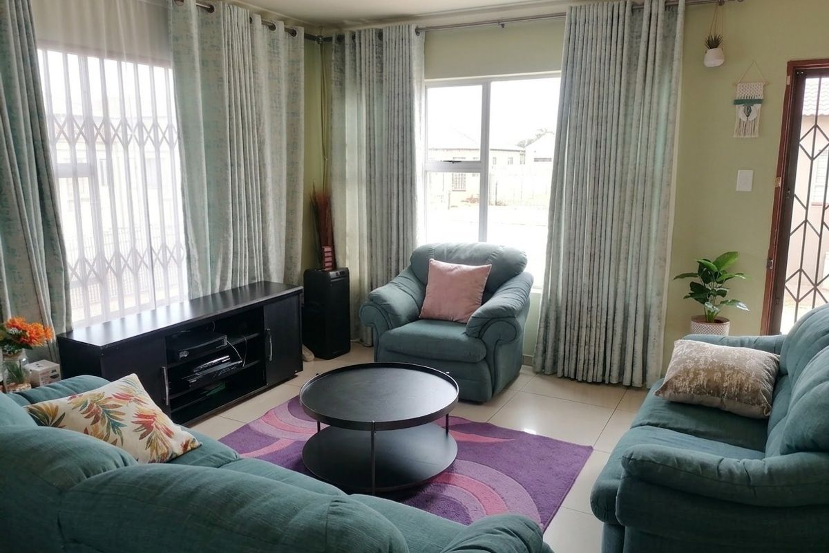 A comfortable living room featuring tiled flooring, large windows with curtain tracks, and a security gate for added peace of mind.