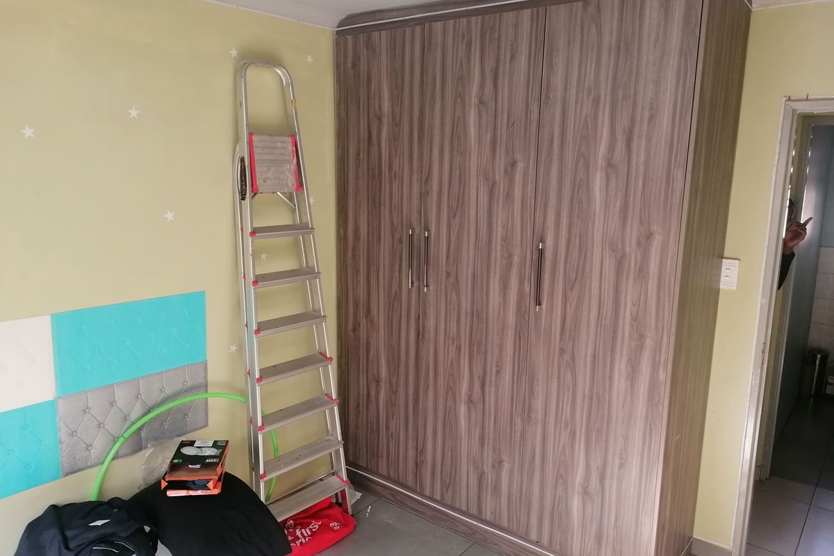 A bedroom featuring a large, wood-grain finish built-in wardrobe and tiled flooring.