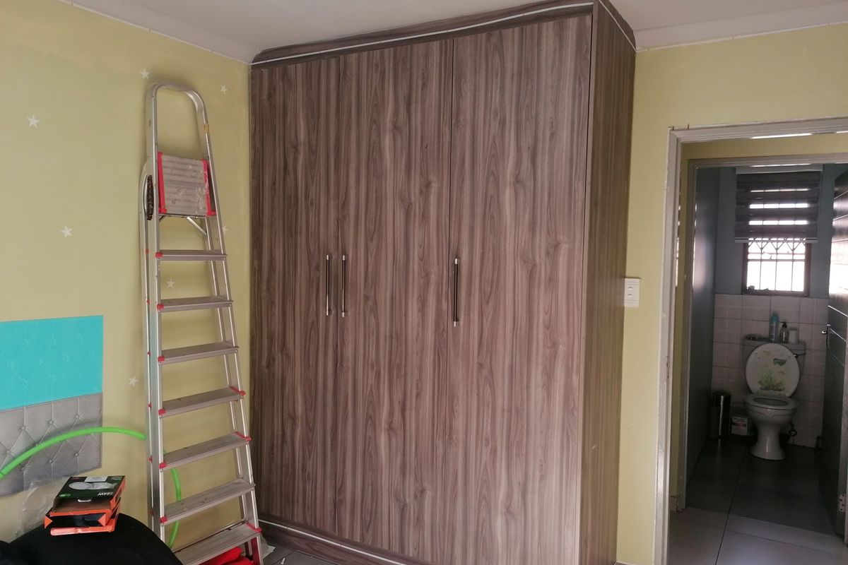 Bedroom featuring a modern wood-grain built-in wardrobe and access to an adjoining bathroom.
