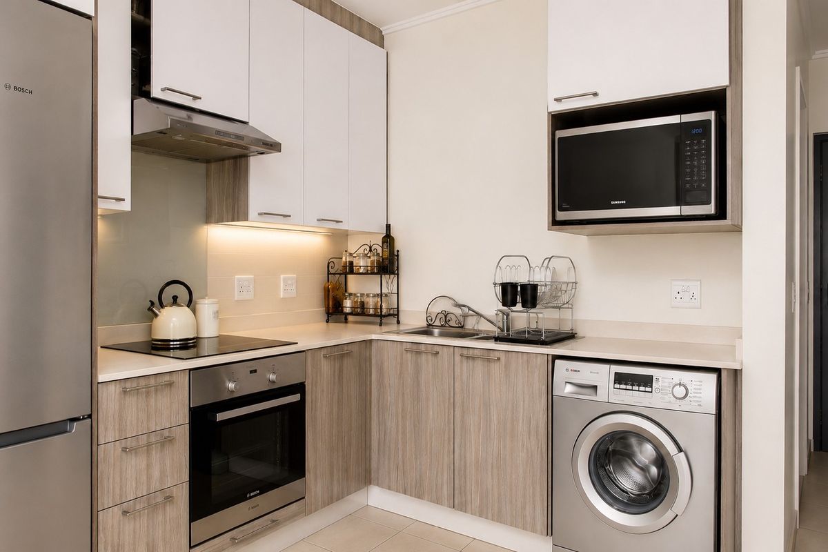 Modern kitchen featuring sleek white and wood-grain cabinetry, stone countertops, integrated appliances, and efficient under-cabinet lighting.