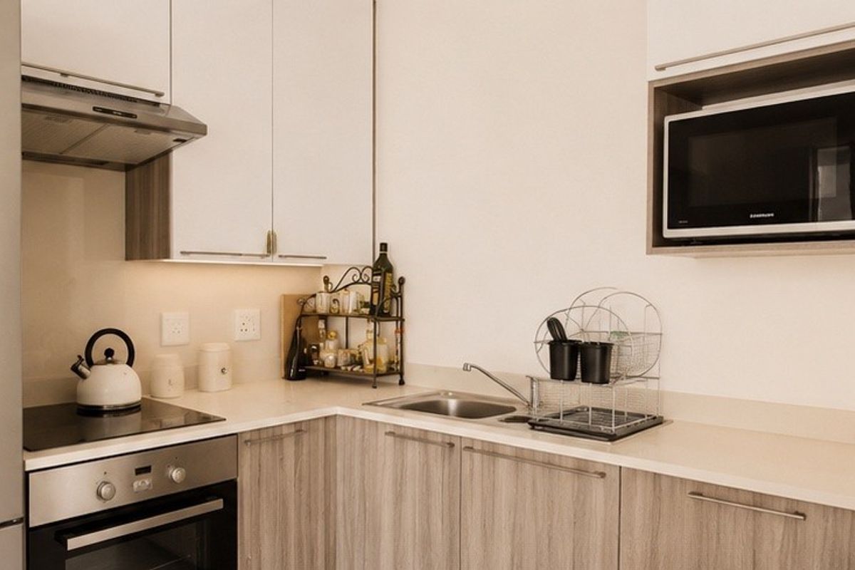 Modern kitchen featuring light wood-grain cabinetry, stone countertops, integrated stainless steel appliances, and a built-in microwave.