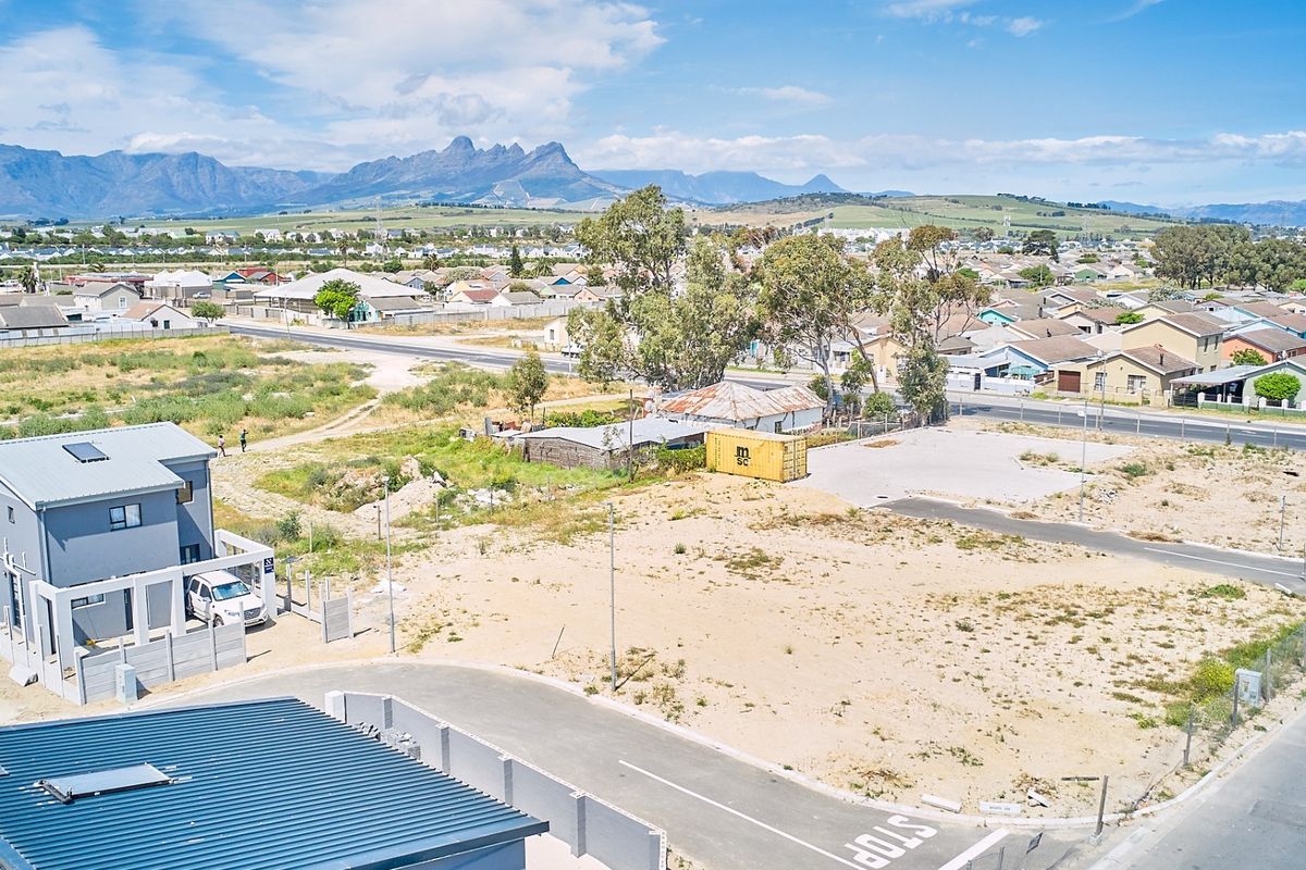 Aerial view of a residential property featuring a modern house, paved driveway, and surrounding neighborhood with mountain views.