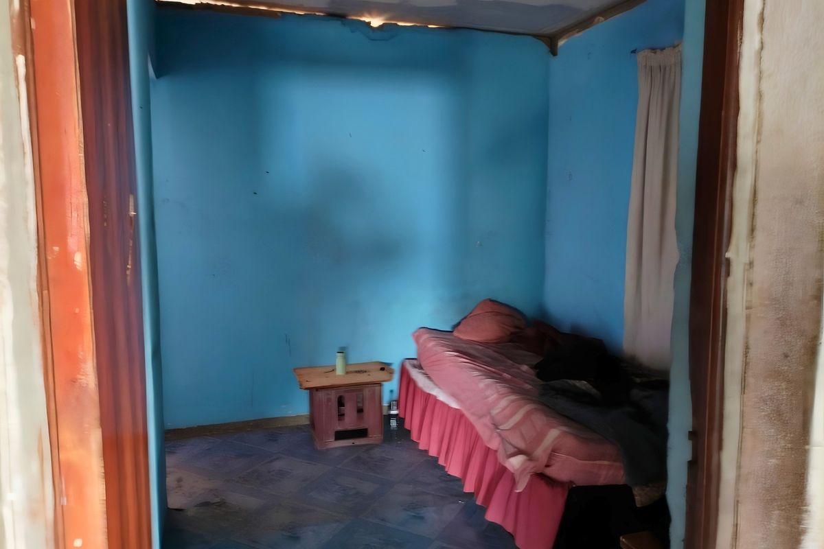 A bedroom space requiring significant renovation, featuring tiled floors and walls in need of repair and repainting.