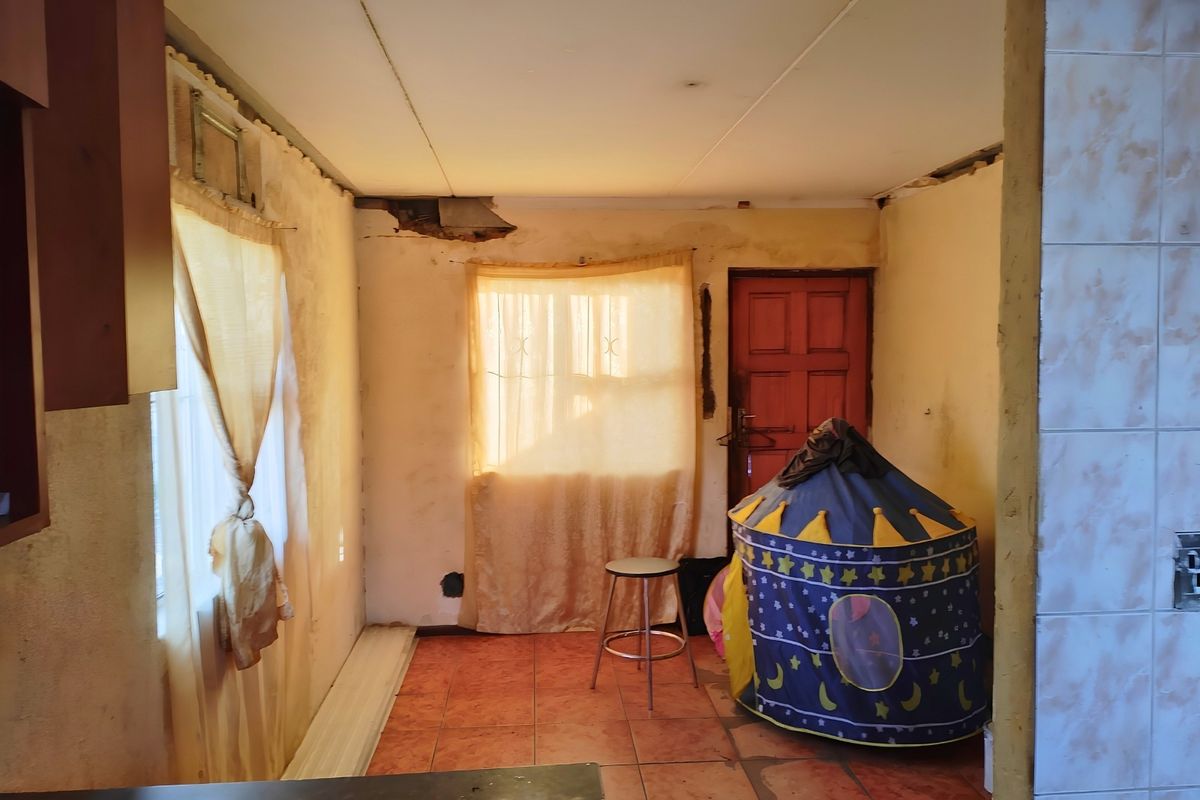 A kitchen area requiring significant renovation, featuring tiled floors and visible damage to the ceiling and wall finishes.