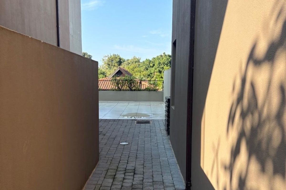 A narrow paved side passage between townhouse structures leading to a rear patio area.