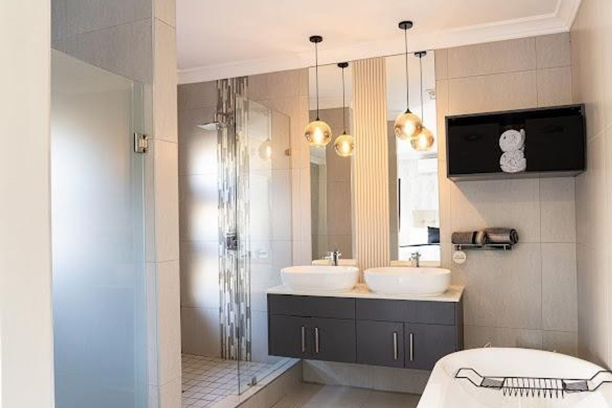 Modern bathroom featuring a double vanity with vessel sinks, a spacious walk-in shower with glass enclosure, and a contemporary freestanding bathtub.