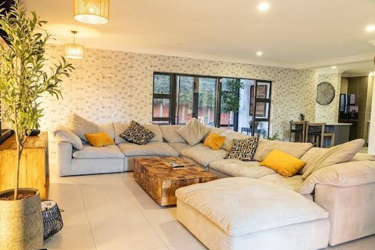Spacious open-plan living area featuring tiled floors, modern recessed lighting, and large sliding glass doors that provide seamless access to the outdoor space.