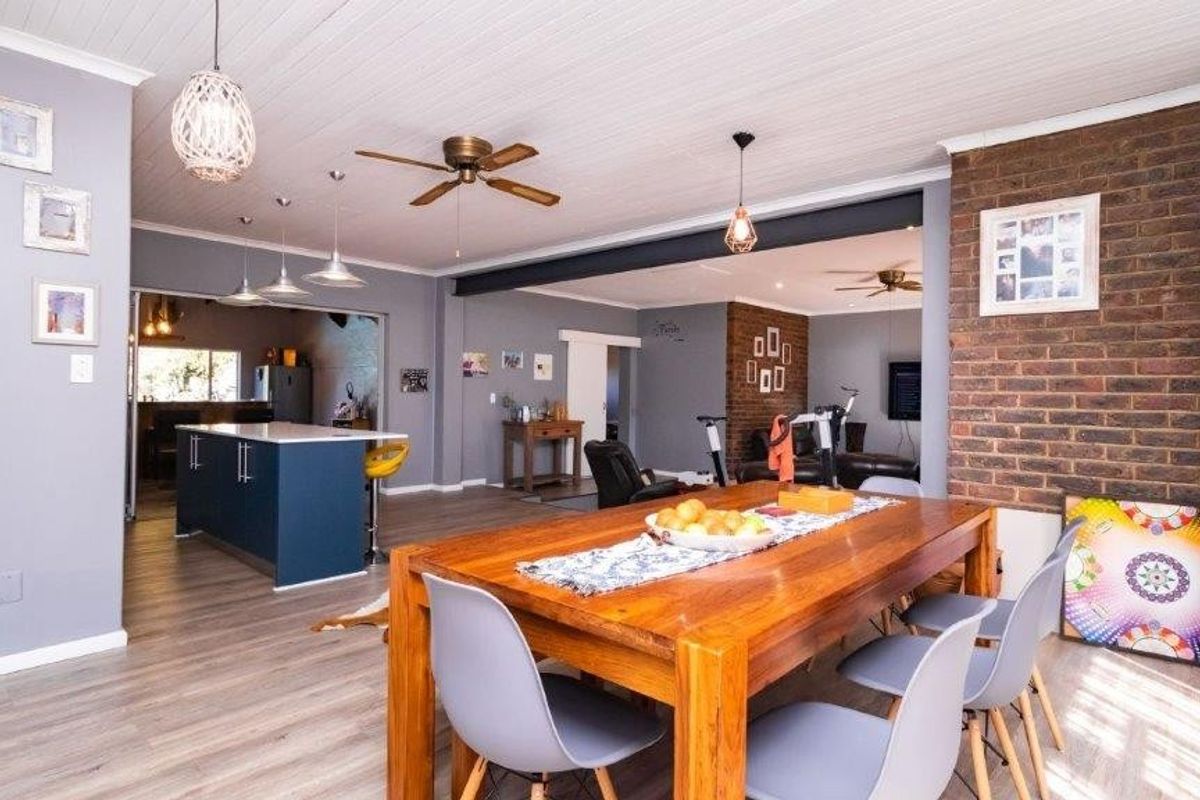 Spacious open-plan living and dining area featuring a kitchen island, exposed brick feature wall, and modern laminate flooring throughout.