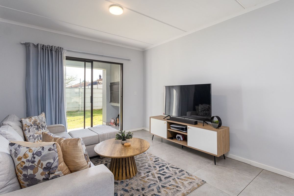 A bright and well-maintained living room featuring large sliding glass doors that provide direct access to the outdoor patio area.