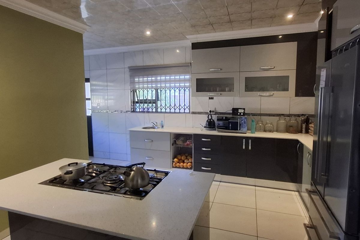 Modern kitchen featuring a central island with a built-in gas hob, sleek cabinetry, tiled finishes, and ample counter space.