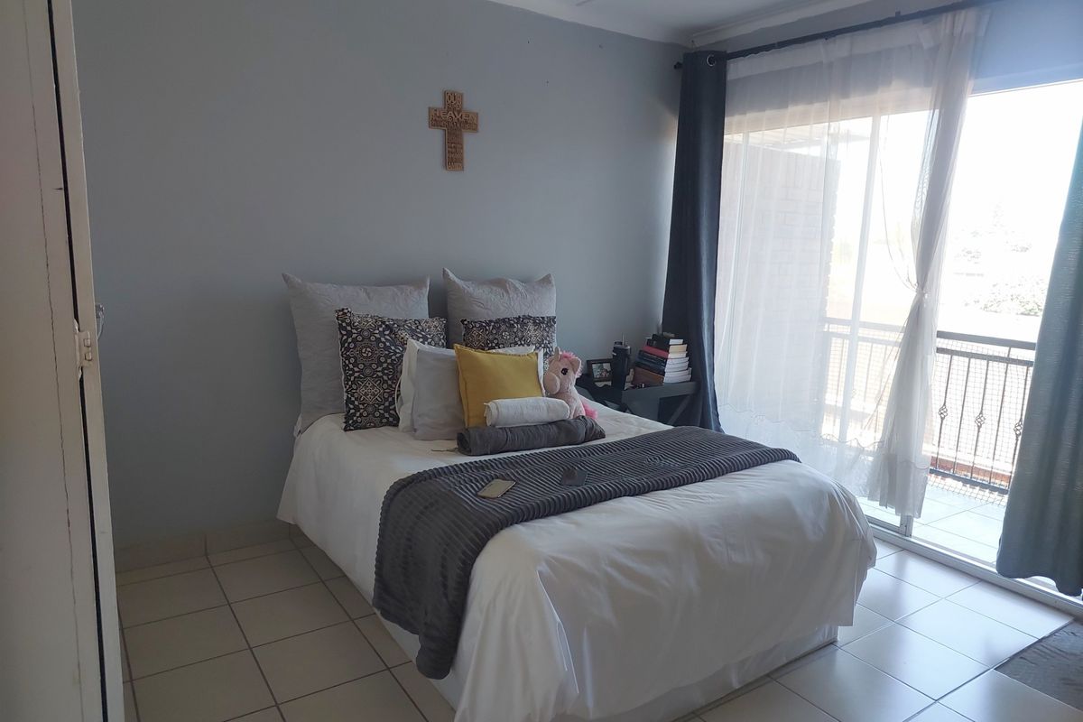 A bedroom featuring tiled flooring and a sliding glass door providing access to a private balcony.