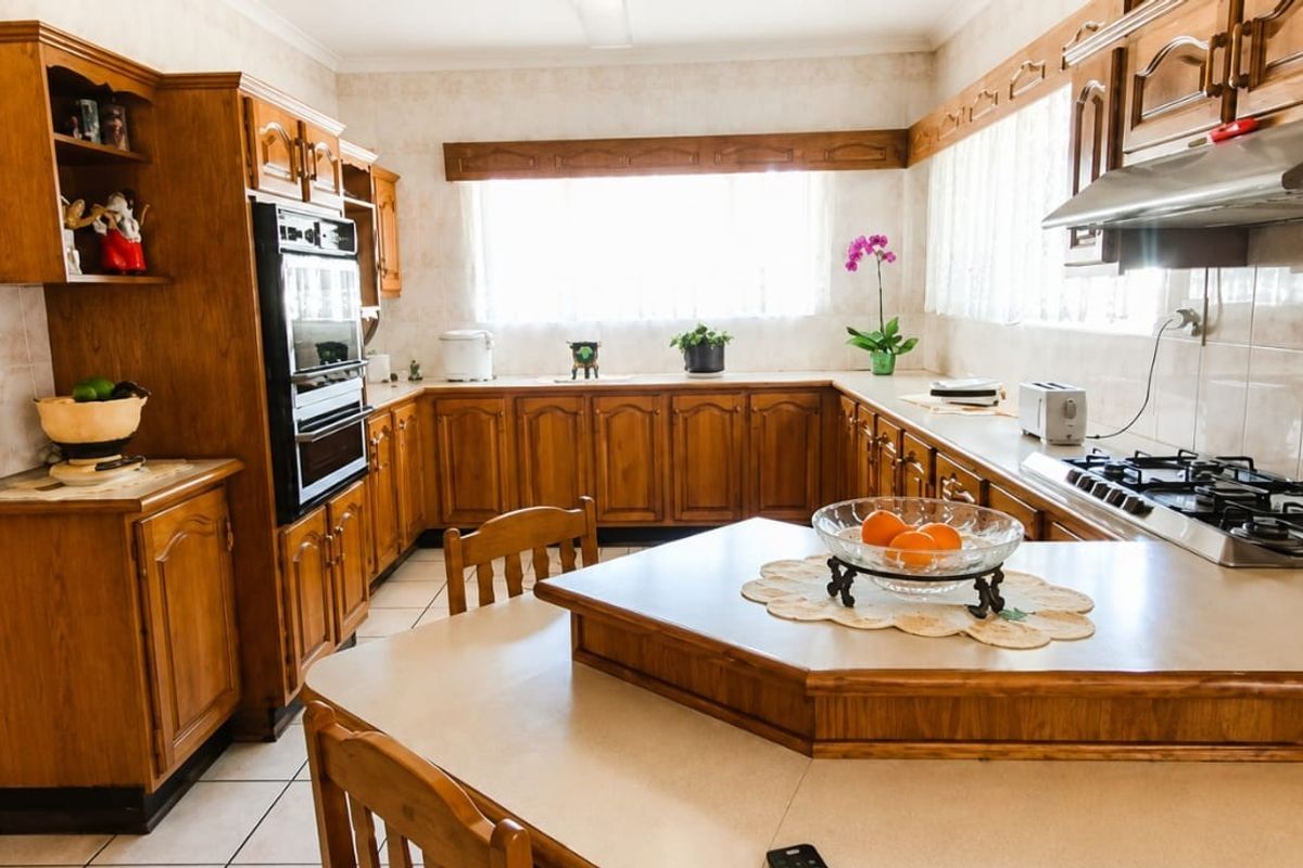 A spacious kitchen featuring traditional wooden cabinetry, built-in oven, gas cooktop, and tiled finishes, offering a functional layout with ample counter space.