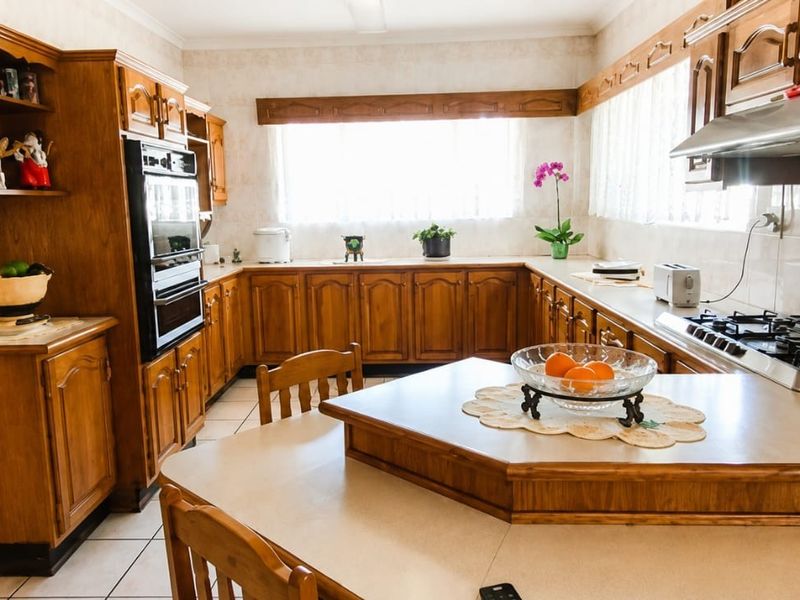 A spacious kitchen featuring traditional wooden cabinetry, built-in oven, gas cooktop, and tiled finishes, offering a functional layout with ample counter space.
