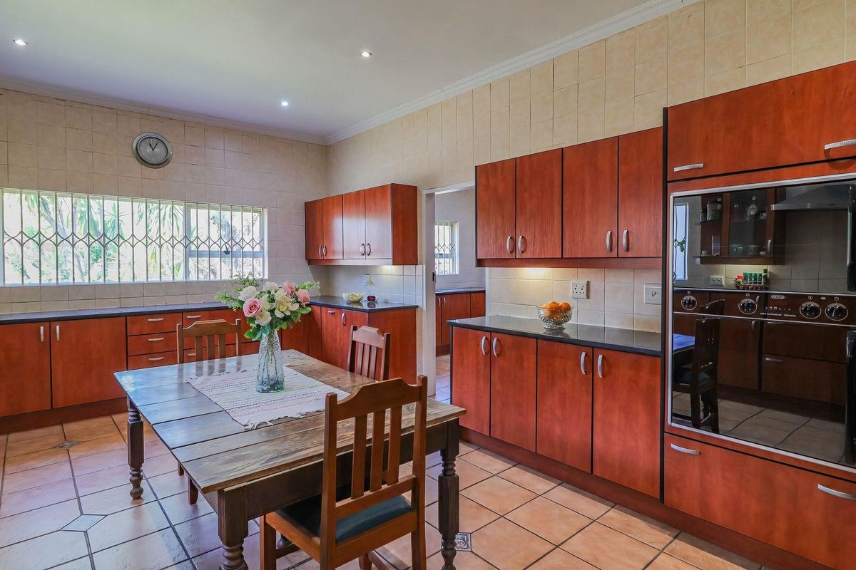 Spacious kitchen featuring warm-toned wooden cabinetry, granite countertops, built-in oven, and tiled flooring, with an integrated dining area and ample natural light.