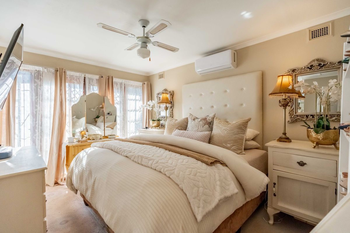 A well-maintained bedroom featuring a ceiling fan, split system air conditioning, and neutral wall finishes, providing a comfortable and functional living space.