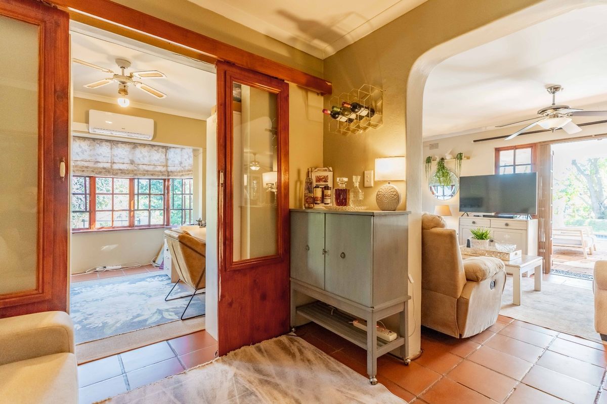 A view through an archway into a living area featuring tiled floors, a ceiling fan, and a sliding wooden door leading to an adjacent room.