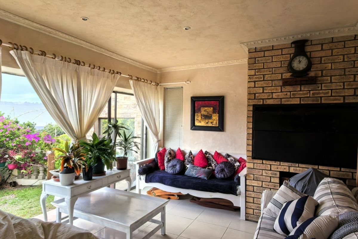 A cozy living room featuring a prominent brick fireplace, tiled flooring, and large sliding glass doors that provide natural light and garden access.