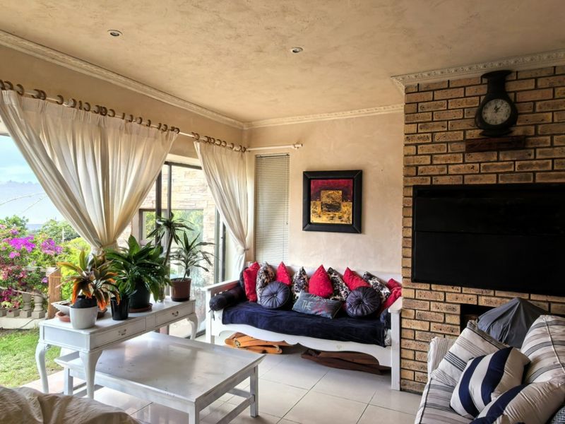 A cozy living room featuring a prominent brick fireplace, tiled flooring, and large sliding glass doors that provide natural light and garden access.