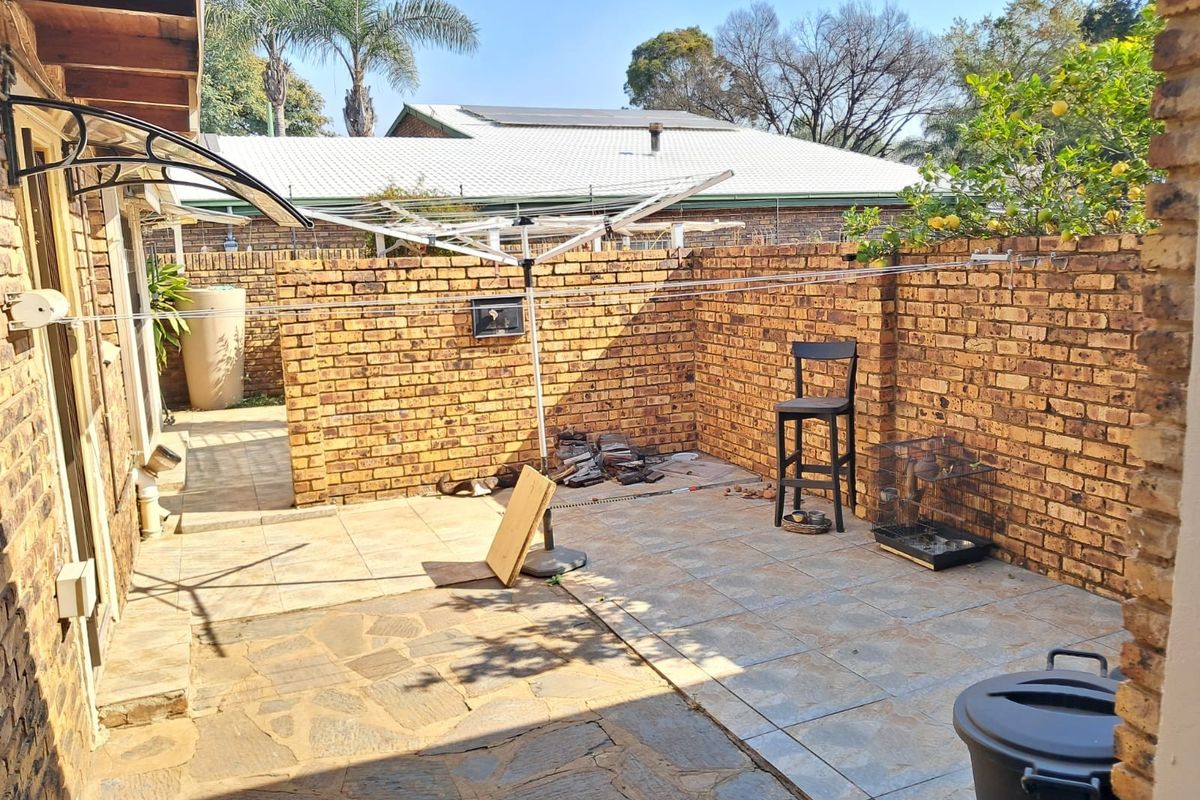 A private rear courtyard featuring brick boundary walls, paved flooring, and a fixed rotary clothesline, offering a functional outdoor utility space.