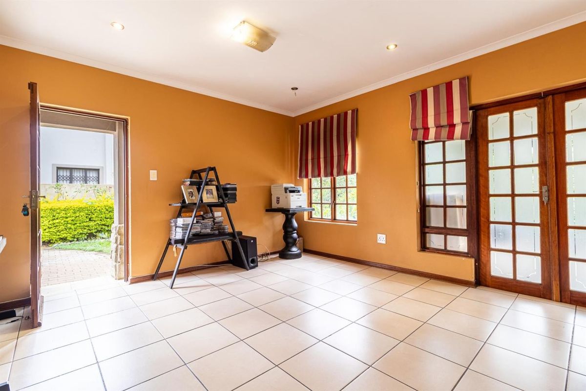 A bright, tiled living area featuring timber-framed glass doors providing direct access to the garden, finished with warm-toned walls and recessed lighting.