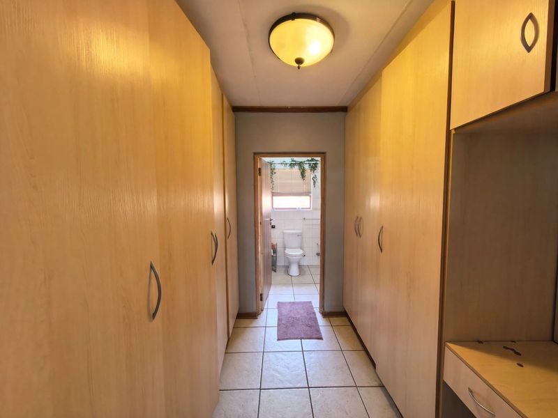 A functional hallway featuring extensive built-in cabinetry for storage, leading directly into a bathroom with tiled flooring throughout.