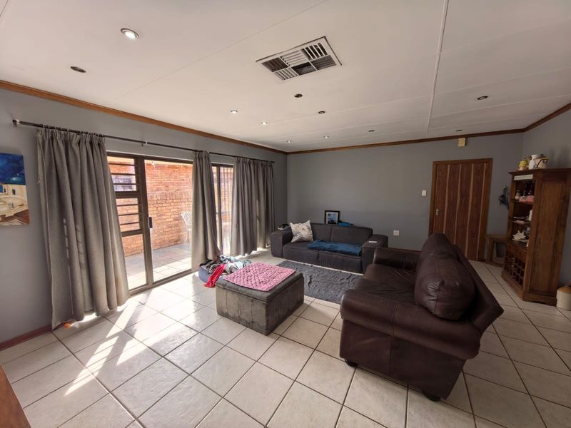 Spacious living room featuring tiled flooring, recessed lighting, ducted air conditioning, and large sliding glass doors providing access to the outdoor area.
