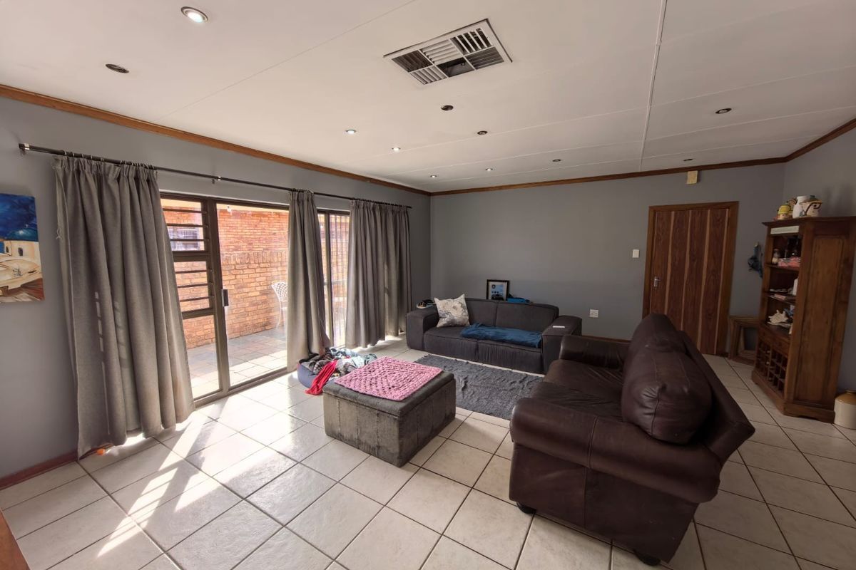 Spacious living room featuring tiled flooring, recessed lighting, ducted air conditioning, and large sliding glass doors providing access to the outdoor area.
