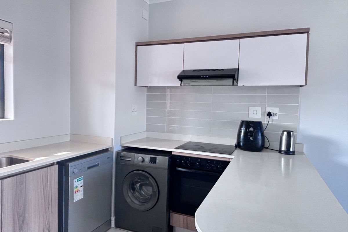 Modern kitchen featuring white and wood-tone cabinetry, stone countertops, subway tile backsplash, and integrated appliances including an oven, hob, and extractor fan.