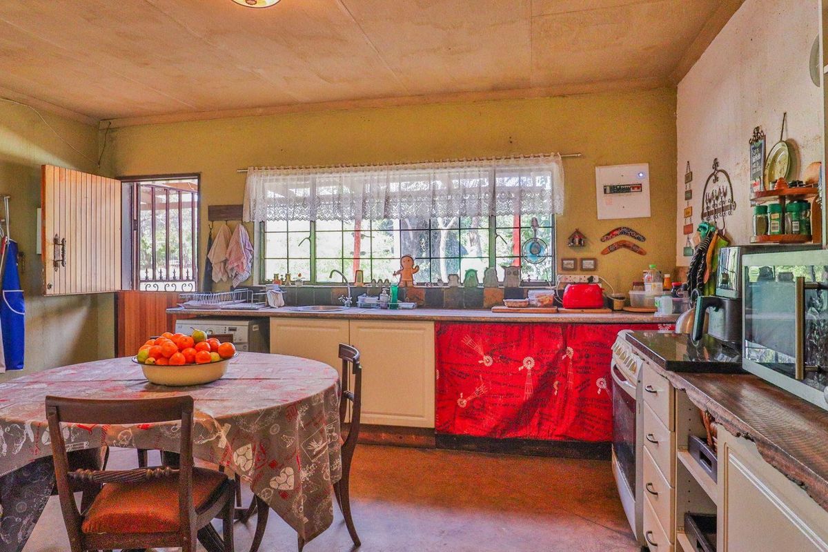 A rustic farm-style kitchen featuring timber countertops, a freestanding stove, and a double sink, with direct access to the exterior via a security gate.