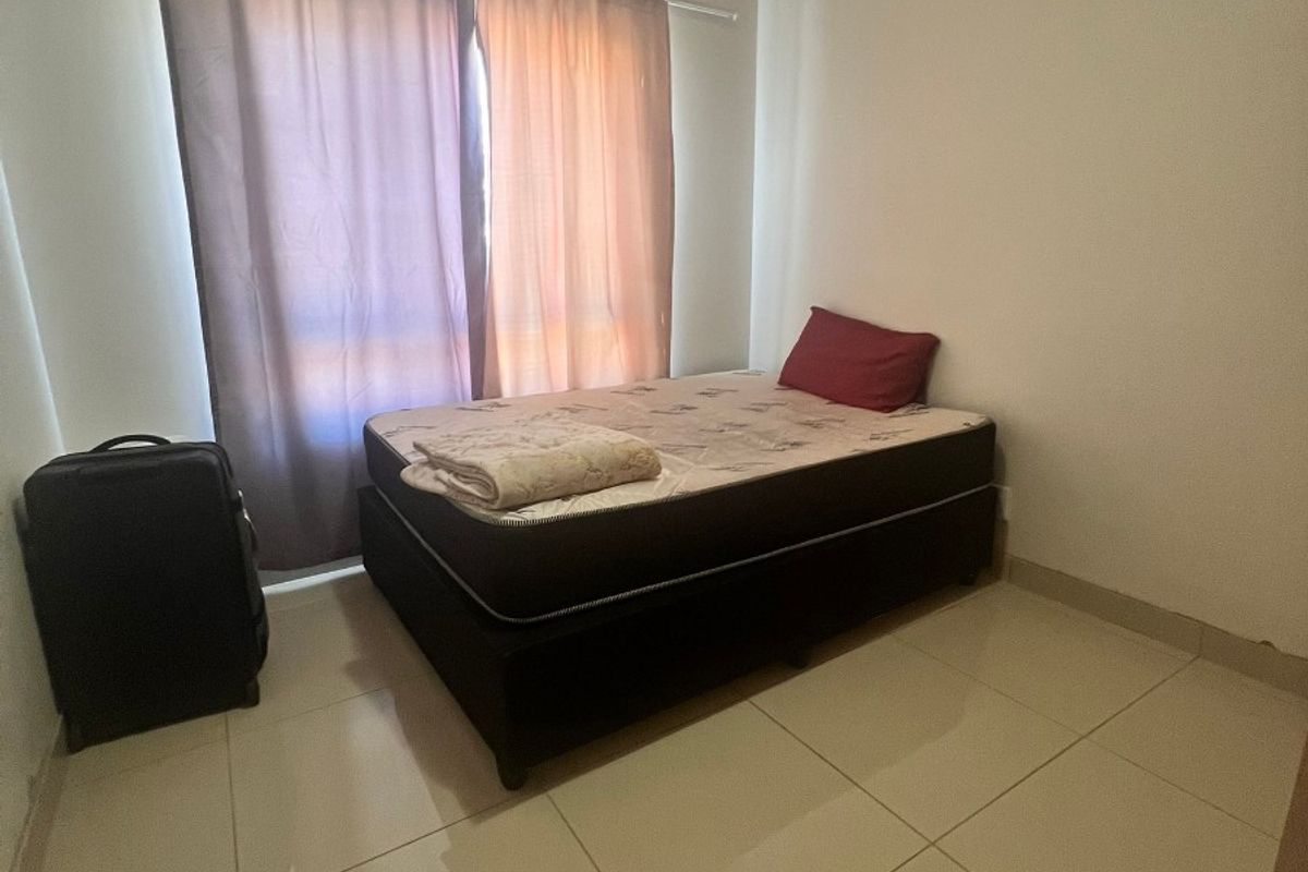 A simple bedroom featuring neutral tiled flooring and a window with installed curtain rails, offering a functional and clean living space.