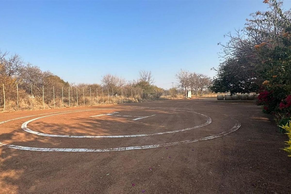 A dedicated helipad area located on the farm grounds, featuring clear markings and perimeter wire fencing.