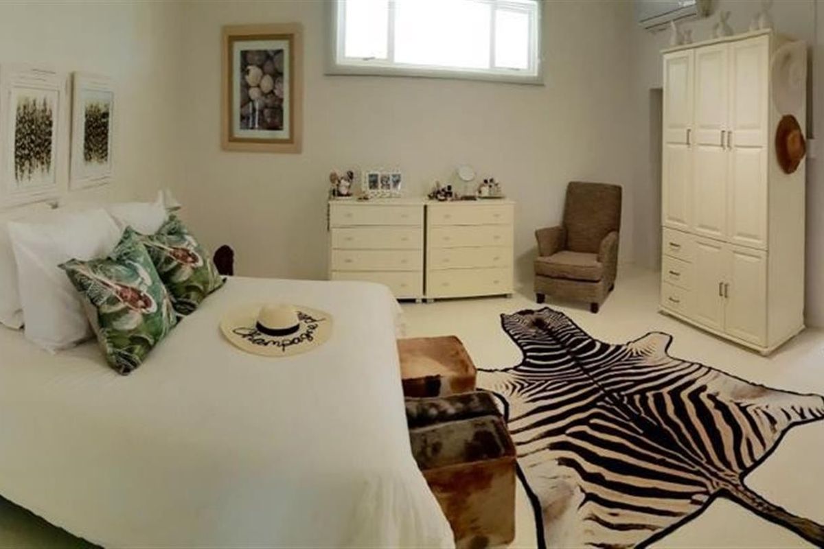 Spacious bedroom featuring a built-in wardrobe, air conditioning unit, and an en-suite bathroom access.