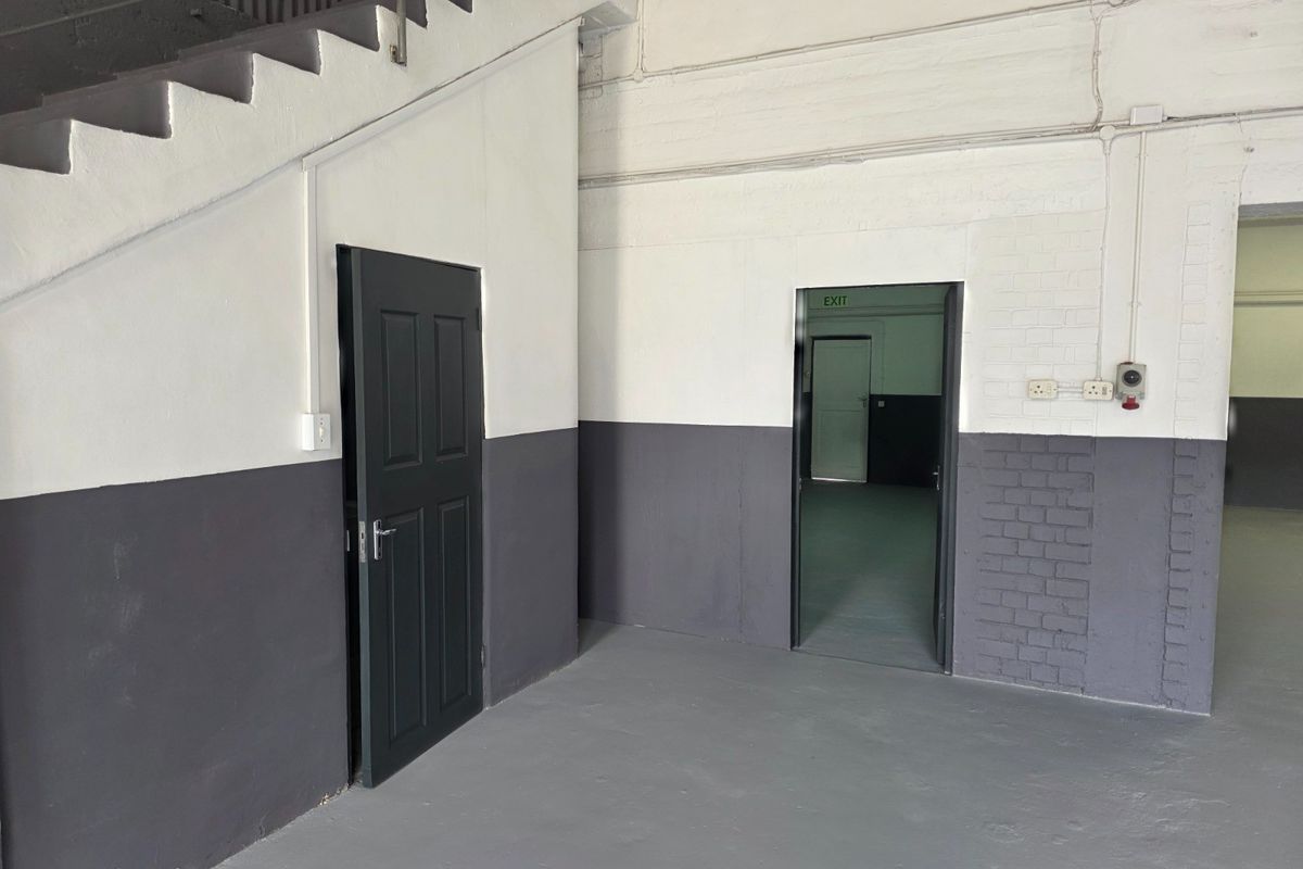 An industrial utility space featuring painted brick walls, a concrete staircase, and multiple access points, suitable for storage or workshop use.