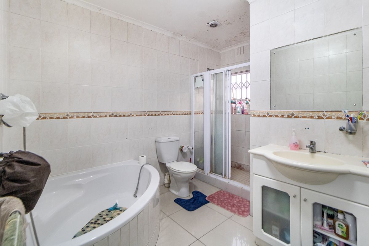 A functional bathroom featuring a corner bathtub, separate shower enclosure, and built-in vanity, requiring cosmetic updates to the ceiling and finishes.